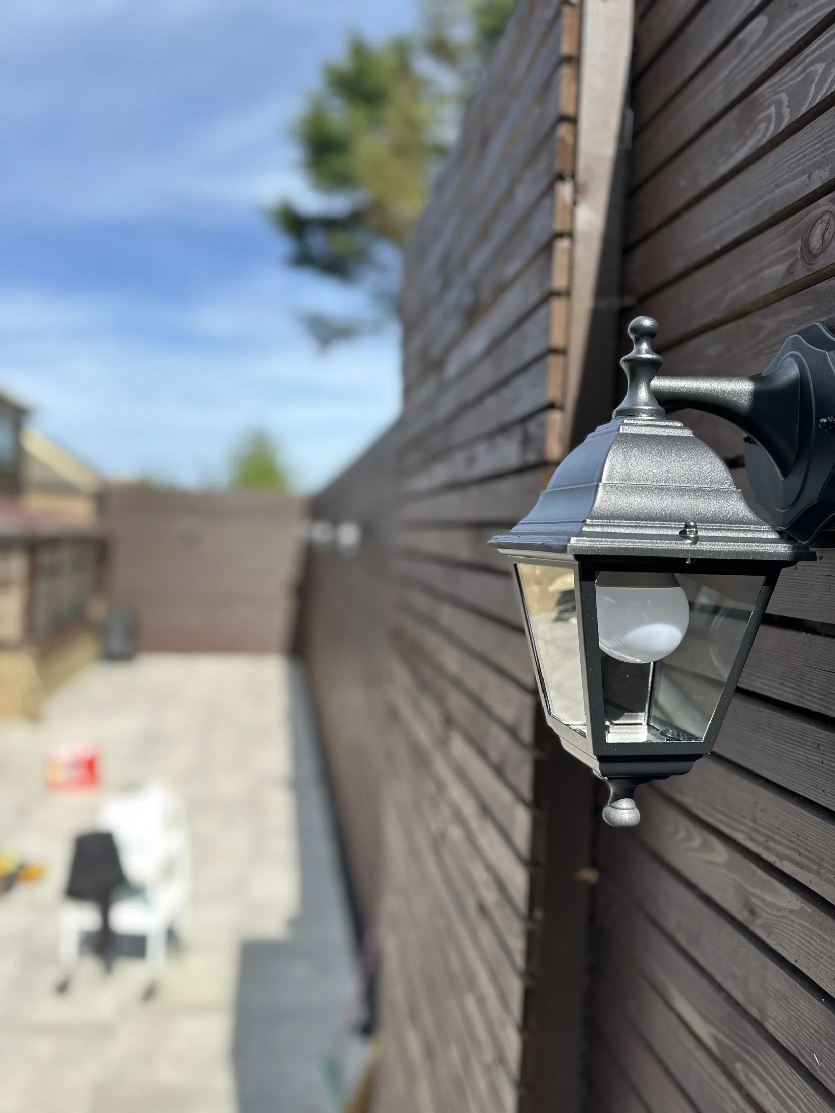 Black exterior wall lantern on timber cladding