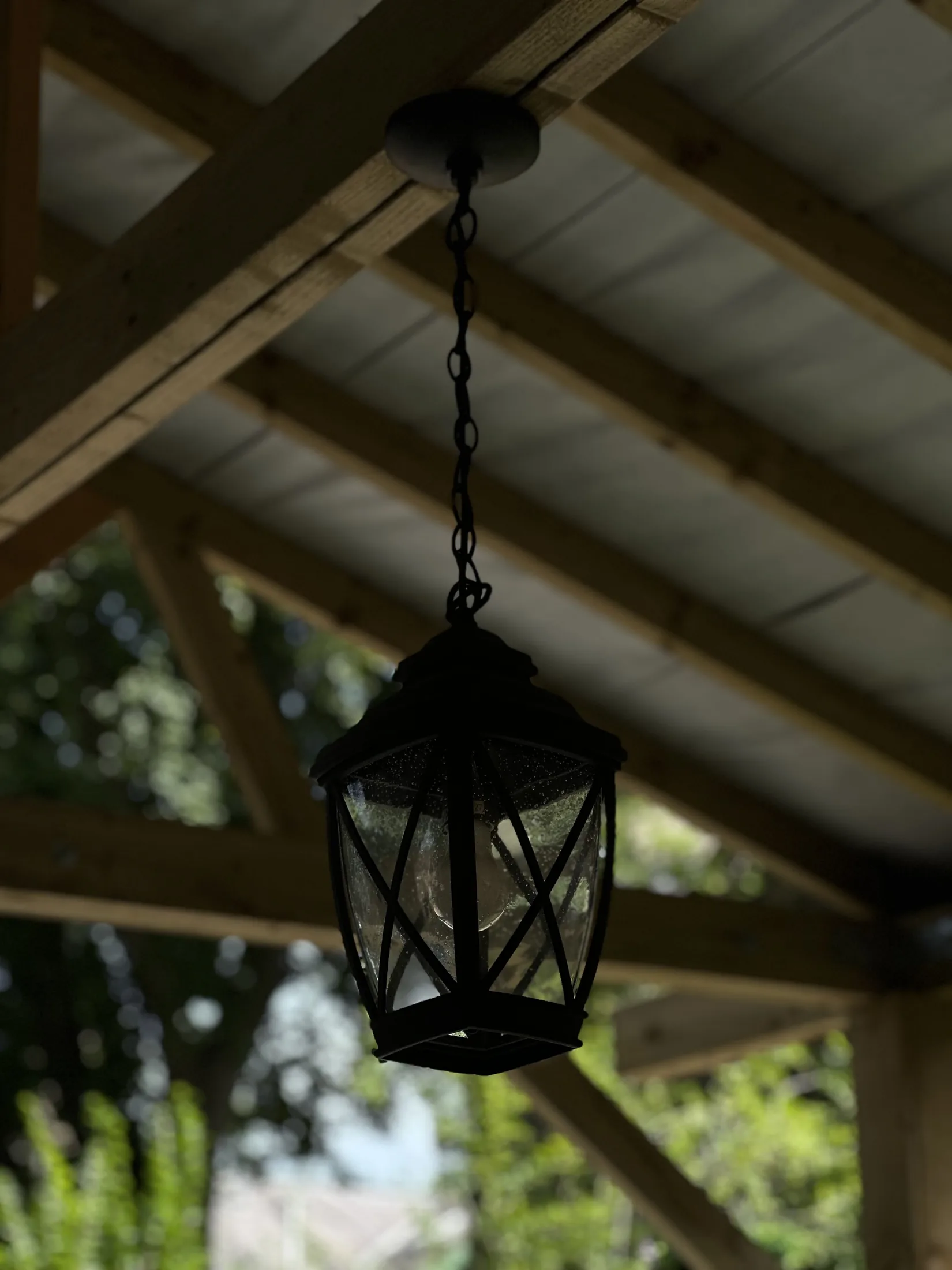 Black hanging lantern suspended from timber beams